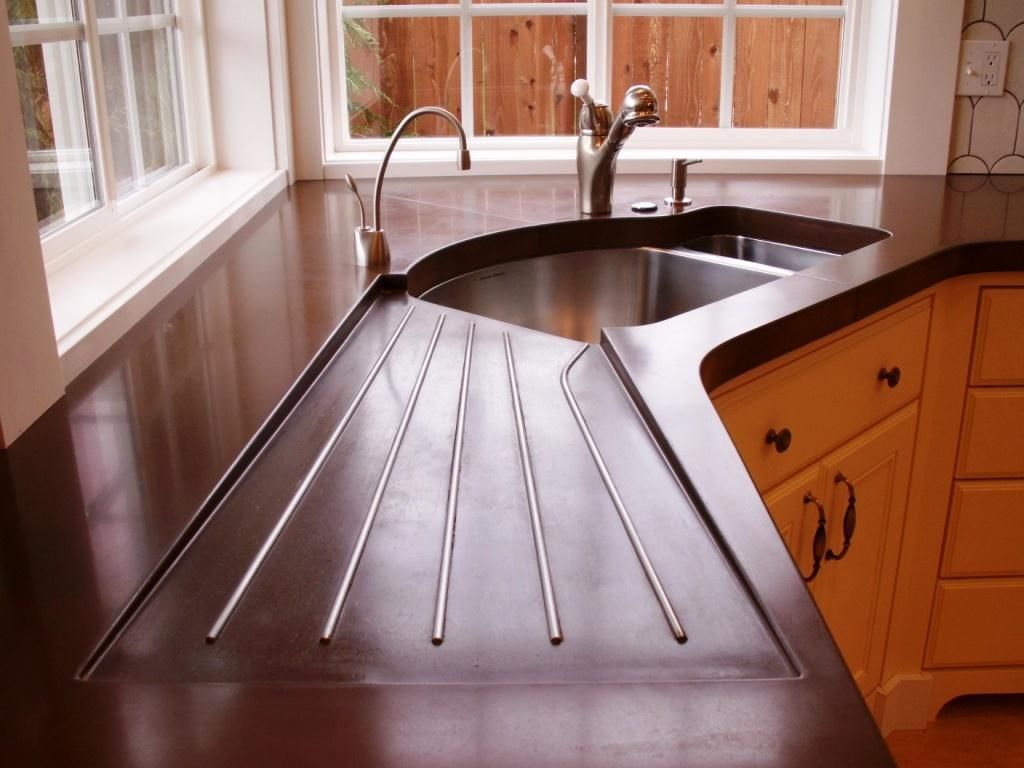 A dark stone countertop with drainboard grooves routed beside an undermount sink