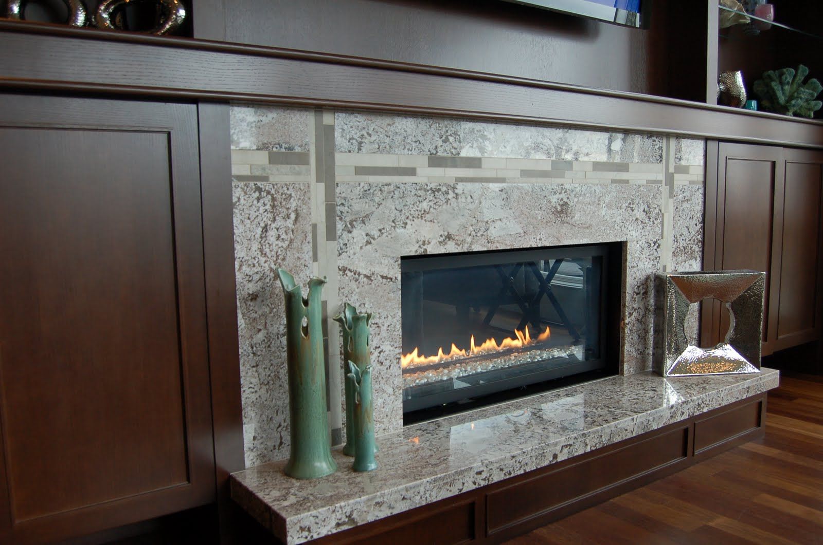 A fireplace surround and hearth in light granite set into dark cabinetry