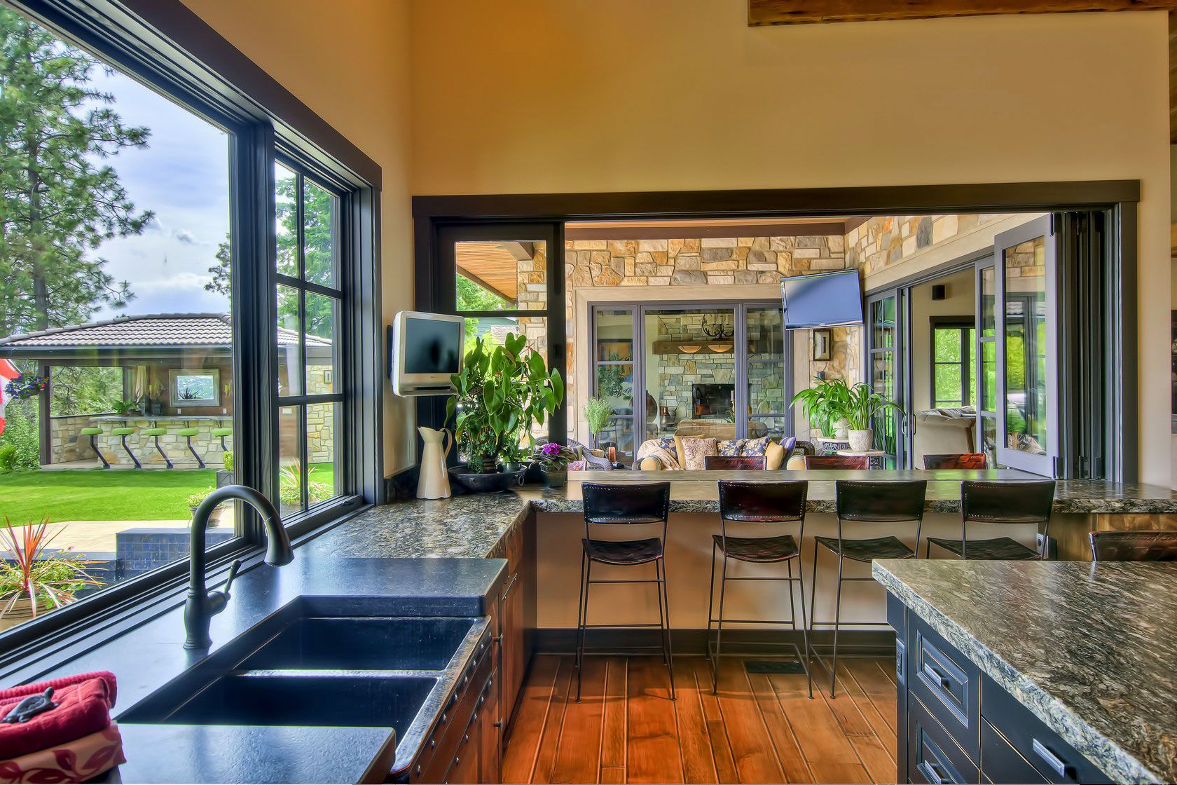 A kitchen with dark granite counters opening onto a garden