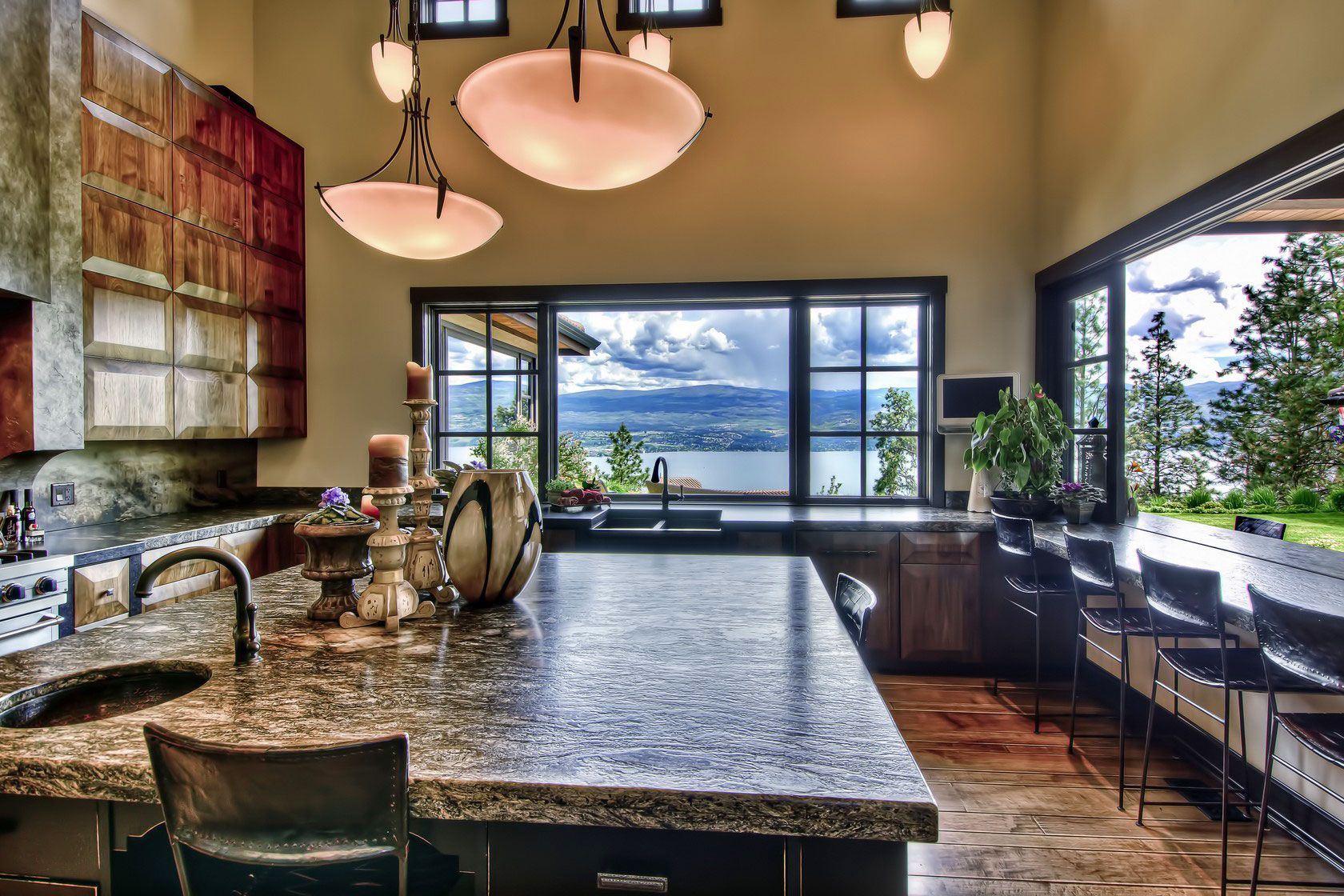 A kitchen island with a textured dark granite top and a view of the lake
