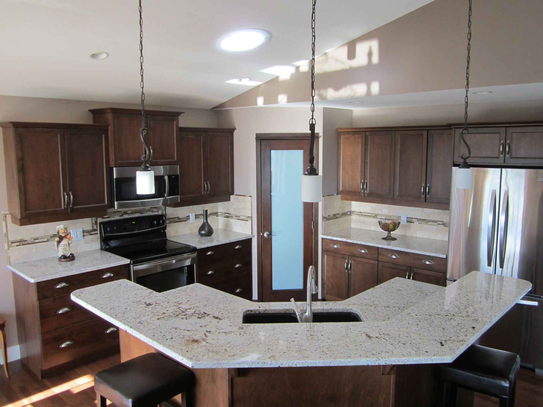An angled kitchen island in white granite with an undermount sink