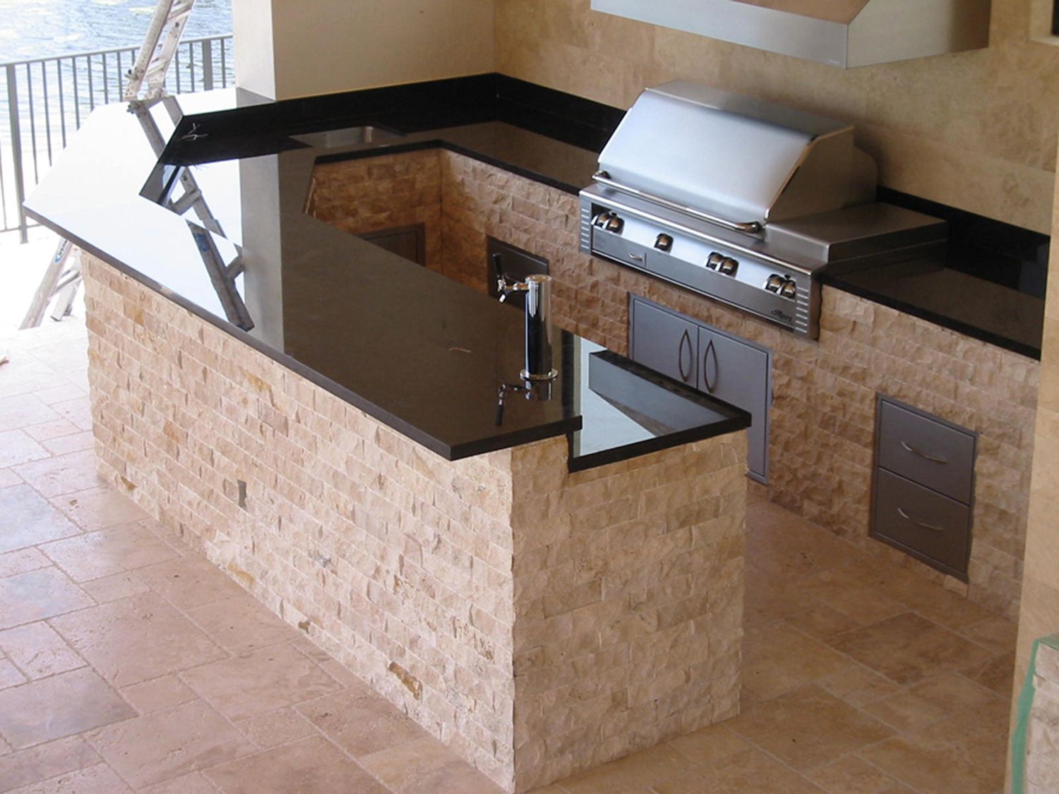 An outdoor kitchen with a black stone top around a built-in grill